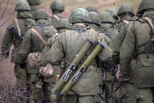 Photo showing the back of a Russian serviceman carrying two rocket launchers.