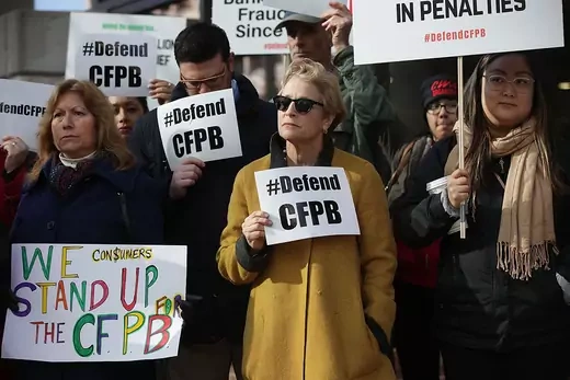Supporters of the Consumer Financial Protection Bureau hold up signs reading "#Defend CFPB" to protest Mulvaney’s appointment.