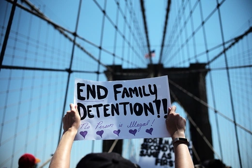 A photo taken on the Brooklyn Bridge shows a protester's hands holding up a sign saying "End Family Detention".