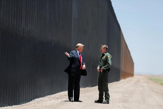 .S. President Donald Trump is seen talking with U.S. Border Patrol Chief in front of border wall.