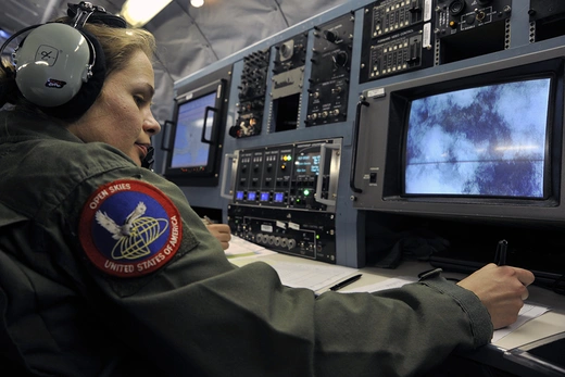 Photo showing a female U.S. Air Force member taking aerial photographs while flying an observation mission. 