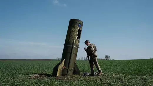 A Ukrainian serviceman looks at a Russian ballistic missile booster that fell in a field in eastern Ukraine.