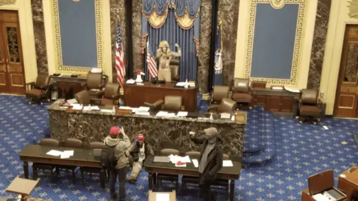 A picture of the Senate chamber at the U.S. Capital with protesters at the podium.