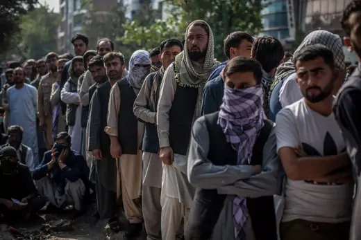 Afghan men wait outside a bank to withdraw money