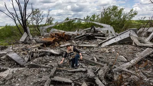 Journalists wearing a "press" vest walks through the site of a destroyed Russian munitions depot in Biskvitne, Ukraine