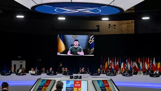 Ukrainian President Volodymyr Zelenskyy appears on a television screen as he delivers a statement at the start of the NATO summit in Madrid.