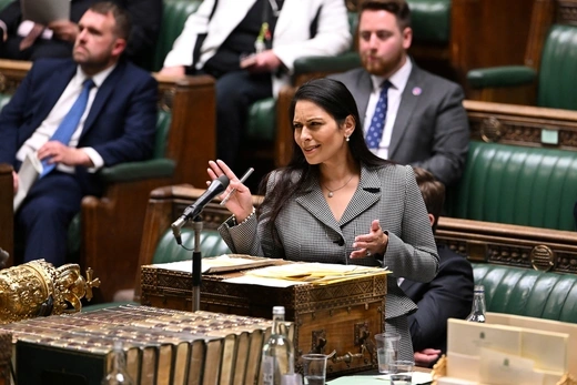 Britain's Home Secretary, Priti Patel, gestures with a confused look to government officials. 