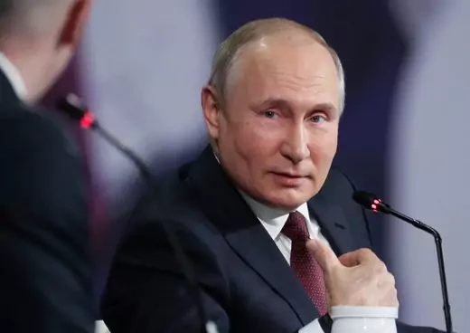Vladimir Putin gestures at a panel.