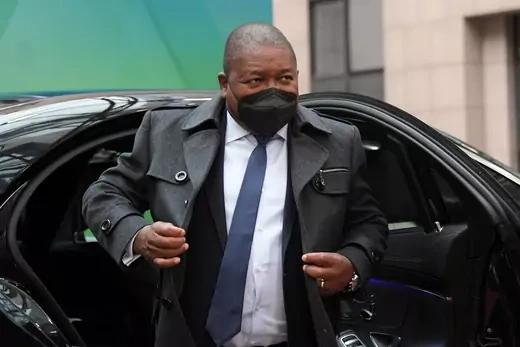 President Filipe Nyusi walks out of a black vehicle with a mask on. 