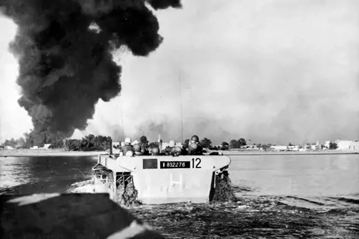 A group of French commandos going ashore during the Suez conflict. Black smoke is billowing in the background.