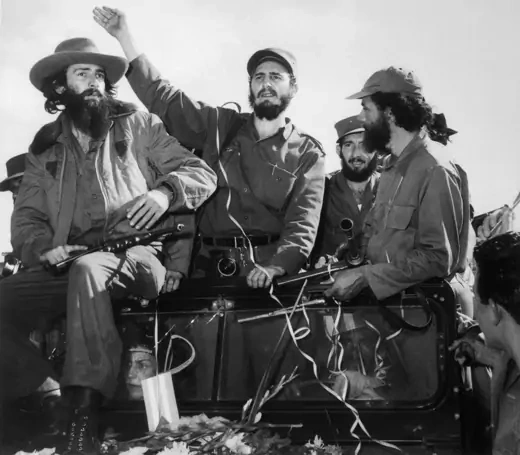  Fidel Castro, surrounded by revolutionaries, waves to a cheering crowd.