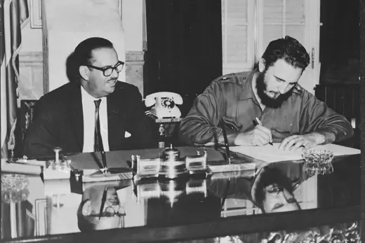Fidel Castro signs decree nationalizing all American-owned banks in Cuba as President Osvaldo Dorticos looks on.