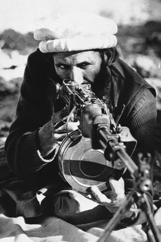 An Afghan tribal rebel poses for a photographer behind the sights of a Soviet-made light machine gun.