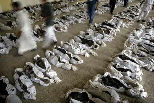 Iraqis walk between hundreds of bodies found in a mass grave.