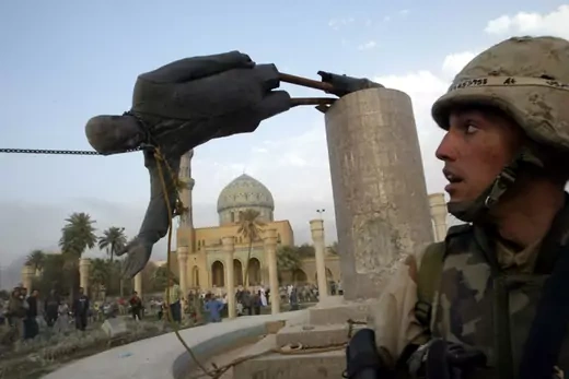 A U.S. Marine watches as a statue of Iraq's President Saddam Hussein falls.