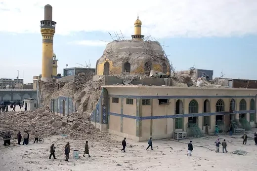 Iraqis walk past the damaged al-Askari mosque following an explosion in Samarra.