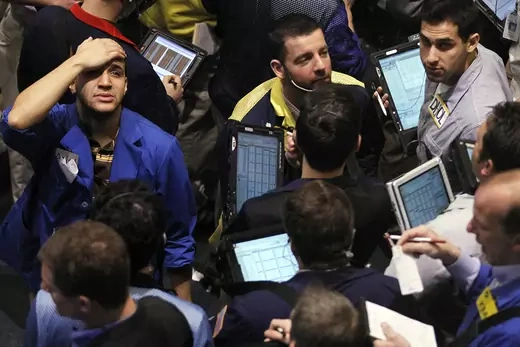 Traders, one holding his head in dismay, are seen on the floor of the New York Mercantile Exchange.