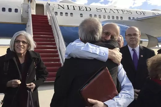 Alan Gross embraces Tim Rieser on the tarmac as he disembarks from a U.S. government plane with wife Judy.