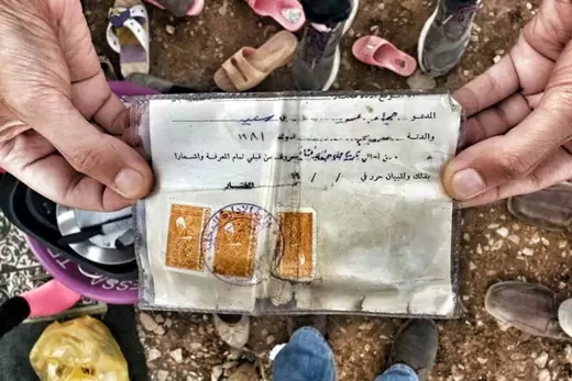 A Syrian refugee shows his "maktoumeen" card, which confers no rights or status and was issued to unregistered stateless Kurds.