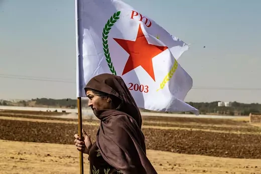 A Syrian Kurdish woman waves the flag of the Democratic Union Party