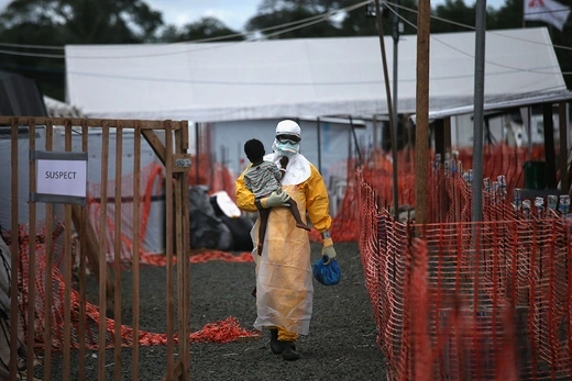 A Doctors Without Borders worker carries a child suspected of having Ebola at a treatment center in Paynesville, Liberia, in October 2014.