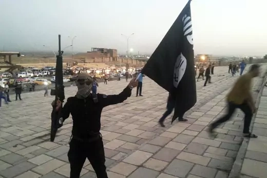 An Islamic State fighter holds a flag bearing the group's symbol on the streets of Mosul, Iraq, on June 23, 2014.  