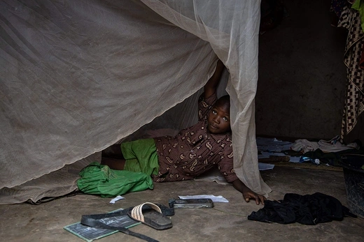 A child lifts his mosquito net in Sao, Burkina Faso, in August 2019.