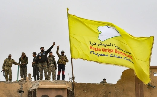 SDF fighters fly a flag in Baghouz.