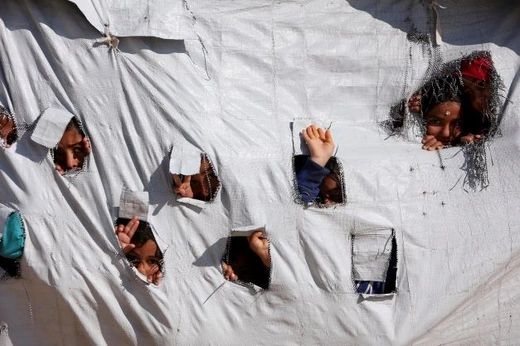 Children look through holes in a tent at al Hol displacement camp in Hasaka governorate, Syria on April 2, 2019.