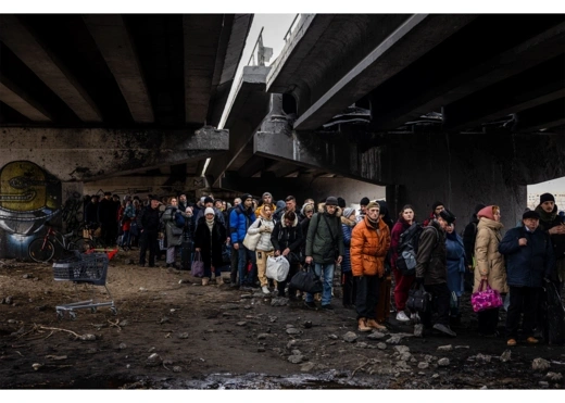 Evacuees stand under a destroyed bridge fleeing the city of Irpin, northwest of Kyiv