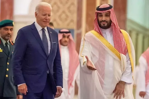 Joe Biden and Mohammed bin Salman walk in front of a group of officials.