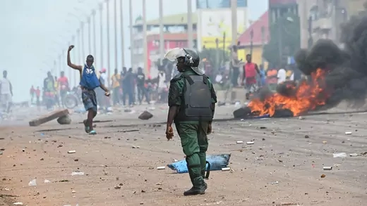 A police officer looks on protesters blocking the road in Conakry, Guinea.