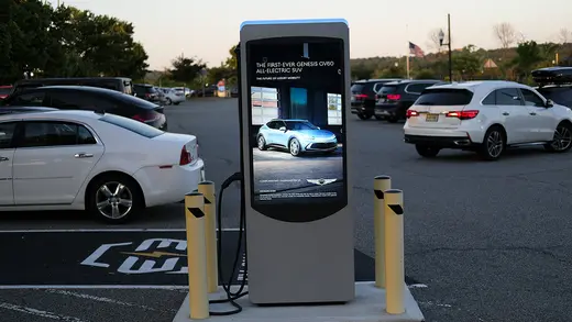 An electric vehicle charging station appears in a parking lot.