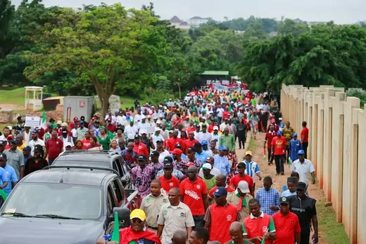 Hundreds of people wearing colorful shirts march in a ralley in Abuja, Nigeria. 