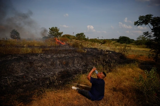 A person takes a break after attempting to put out a brush fire during a drought in Nanchang, China. Thomas Peter/Reuters