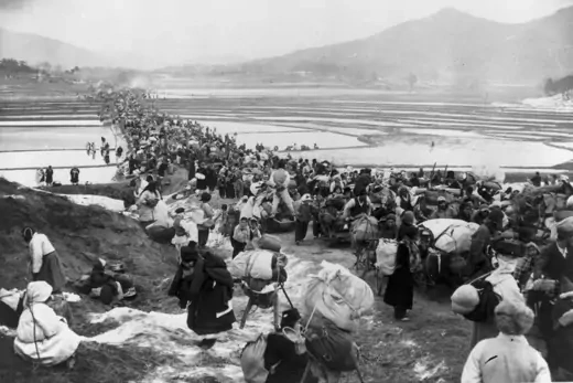 South Korean refugees block the road bridge across rice paddies as they flee advancing Communists South of Seoul
