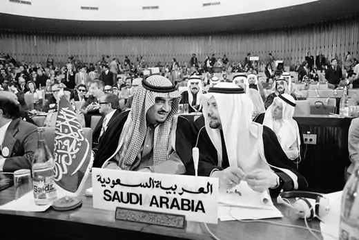  King Fahd and Sheikh Ahmed Zaki Yamani of Saudi Arabia speaking in a large room filled with other delegates