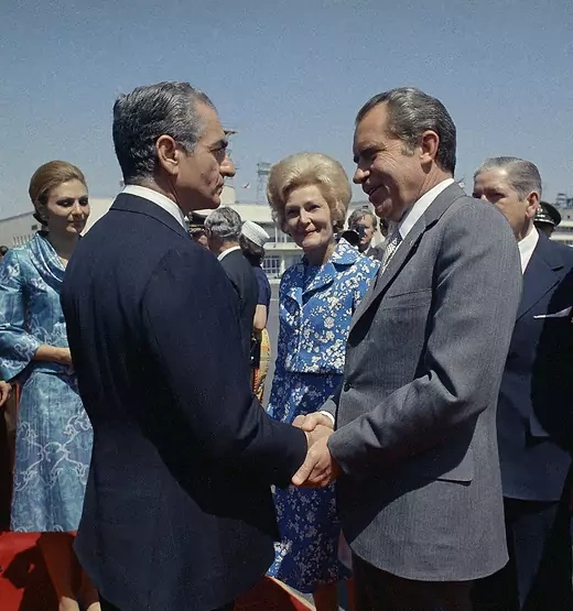 President Richard Nixon and Shah Mohamed Reza Pahlavi shake hands. Their wives and other officials stand in the background.