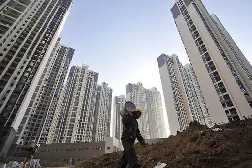A construction worker walks among high-rise apartment blocks in China’s Hubei Province.