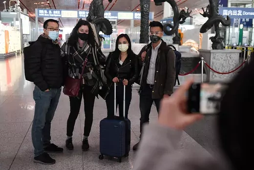 Four people wear face masks and pose for a photo in the Beijing airport. 