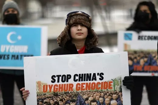 A boy holds a sign that reads "Stop China's Uyghur Genocide." 
