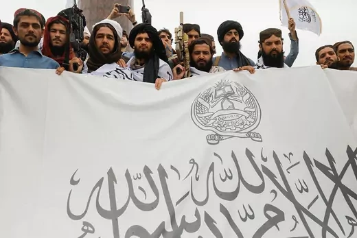 Taliban fighters hold a flag for the Islamic Emirate of Afghanistan.