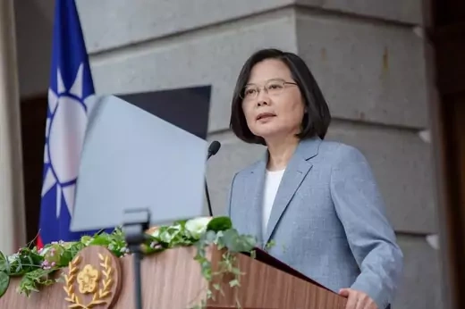 Tsai Ing-wen stands at a lectern with a microphone and a Taiwanese flag in the background.