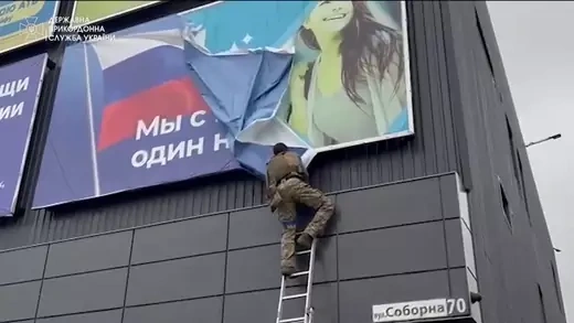 A Ukrainian soldier rips down a banner, amid Russia's invasion of Ukraine, in Vovchansk, Ukraine in this image from a video released September 13, 2022. State Border Service of Ukraine/Handout via REUTERS 