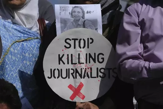 A Pakistani journalist holds a sign and a picture of AP photographer Niedringhaus, who was killed in Afghanistan, during a demonstration to condemn attacks against Journalists in Islamabad