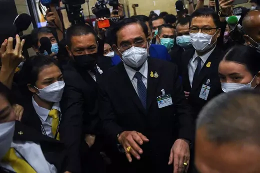 Man walks through crown of reporters, wearing suit and face mask
