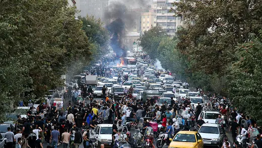Protesters weave through cars on a street in Tehran during a demonstration over the death of Mahsa Amini.