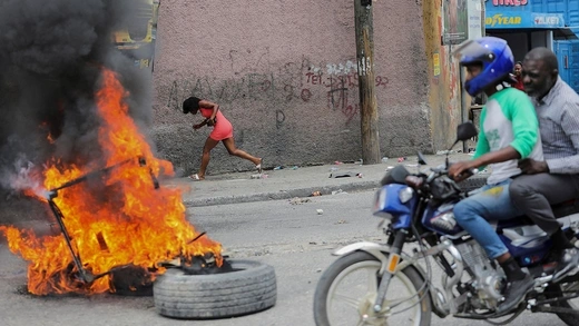 A woman runs past a burning barricade during a protest against growing fuel scarcity, soaring consumer prices, and crime in Port-au-Prince, Haiti, on August 29, 2022.