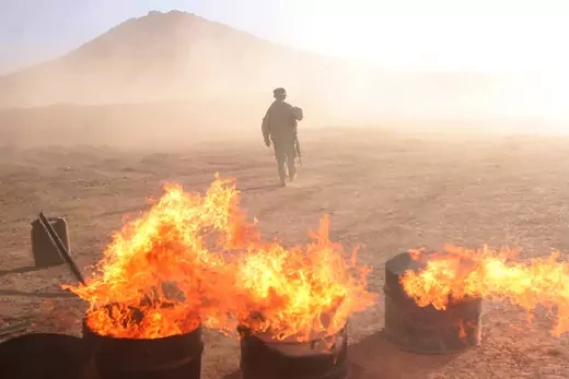 A U.S. soldier walks next to burning waste outside a new US military base.
