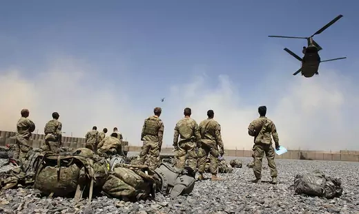 U.S. soldiers looking at helicopters carrying U.S. Army soldiers.